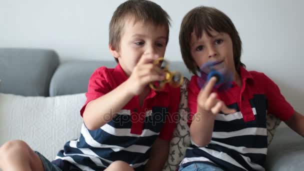 Crianças pequenas, irmãos meninos, brincando com brinquedos coloridos fidget spinner para aliviar o estresse em casa — Vídeo de Stock