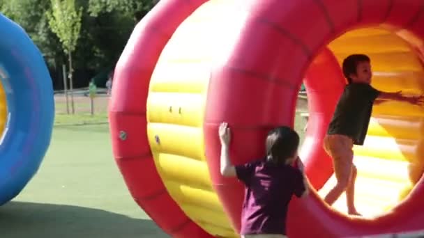 Niedliche kleine Jungen, die in einem rollenden Plastikzylinderring mit einem Loch in der Mitte spielen, im Freien — Stockvideo