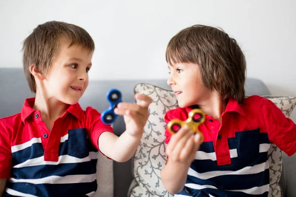 Filhinhos, meninos irmãos, brincando com fidget spin colorido — Fotografia de Stock