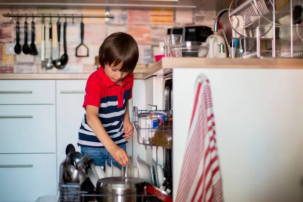 Criança pré-escolar, menino, ajudando a mãe, colocando pratos sujos na louça — Fotografia de Stock