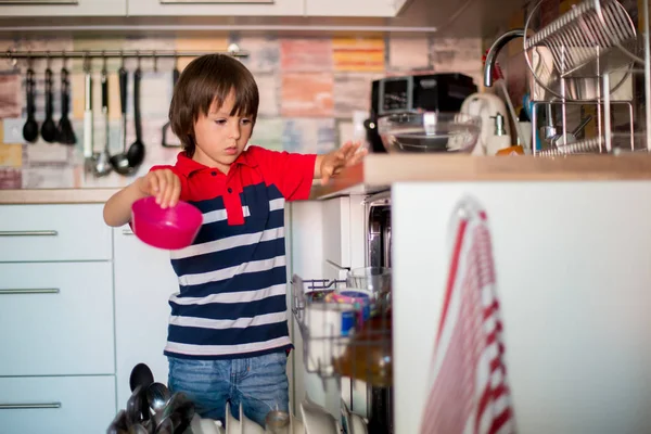 Дошкольный ребенок, мальчик, помогает маме, кладет грязную посуду в посуду — стоковое фото