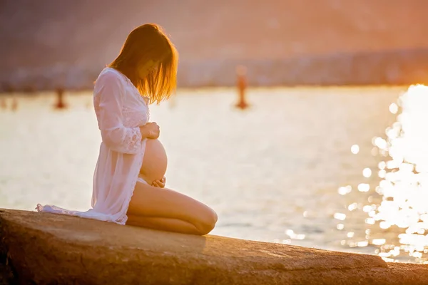 Belle femme enceinte, assise sur le rivage sur la plage sur s — Photo