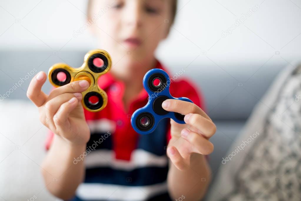 Little child, boy, playing with two fidget spinner toys