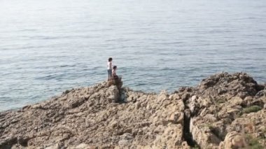 İki çocuk, çocuklar, eğleniyor deniz kıyısında kayalar üzerinde çalışan