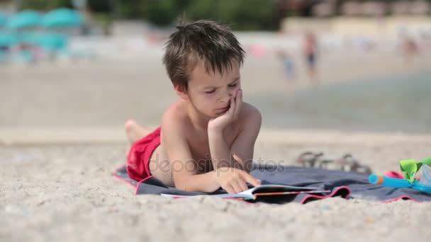 Szkoła dziecka, czytanie książki na plaży, aby przygotować się do szkoły na słoneczny weekend — Wideo stockowe