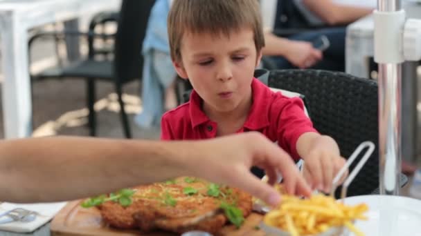 Okul öncesi çocuk, büyük biftek et ve patates kızartması bir restoranda yemek — Stok video