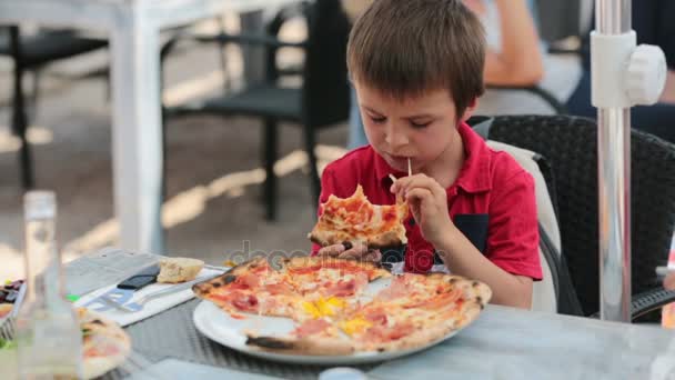 Meninos felizes, sentados à mesa no restaurante, comendo pizzas, sentados à mesa no restaurante, comendo pizza — Vídeo de Stock