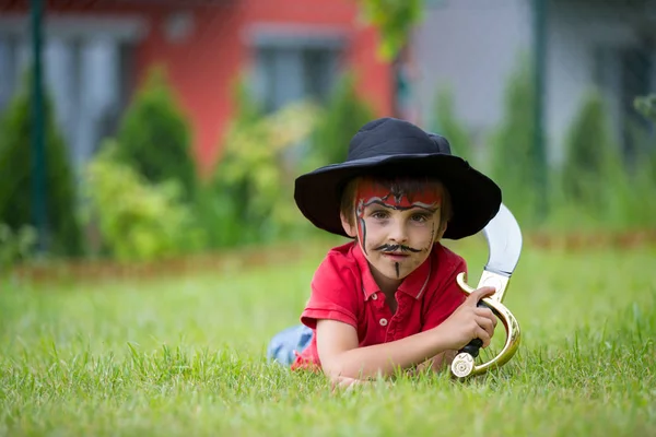 Lindo chico de la escuela, jugando juegos, pintado como pirata, sosteniendo la espada —  Fotos de Stock