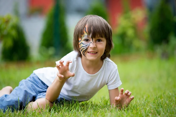 Dolce bambino prescolare, dipinto come tigre, che gioca in giardino — Foto Stock