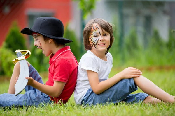 Zwei Kinder, Brüder, gemalt als Tiger und Pirat, spielen in — Stockfoto