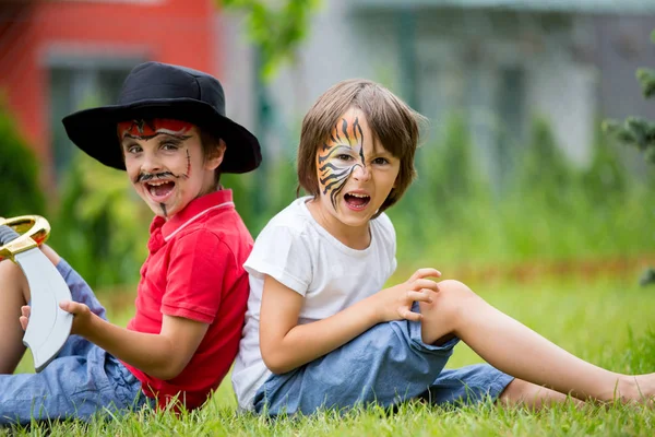 Zwei Kinder, Brüder, gemalt als Tiger und Pirat, spielen in — Stockfoto