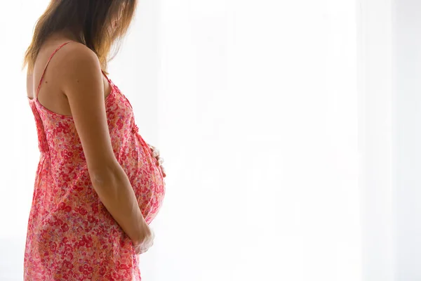 Portrait de jeune femme enceinte attrayante, debout par la victoire — Photo