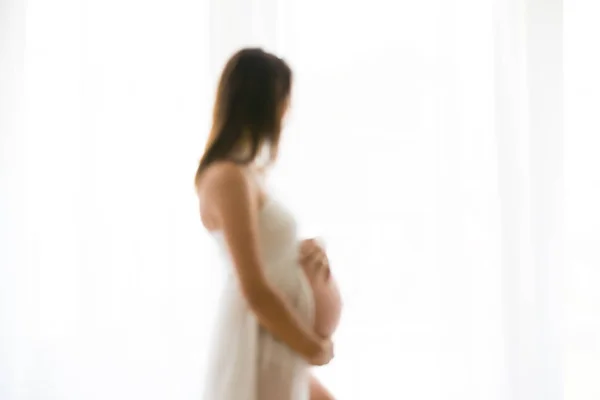 Zamazany obraz młoda kobieta w ciąży atrakcyjne, stojąc przez th — Zdjęcie stockowe
