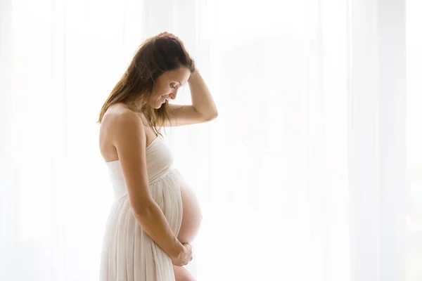 勝利によって立っている若い妊娠中の魅力的な女性の肖像画 — ストック写真