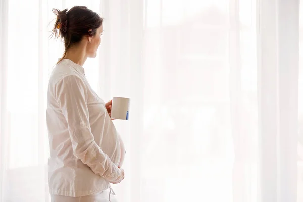 Portrait de jeune femme enceinte attrayante, debout par la victoire — Photo