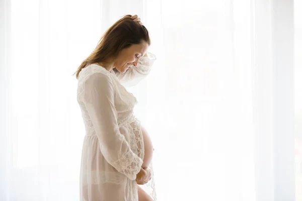 Portrait de jeune femme enceinte attrayante, debout par la victoire — Photo