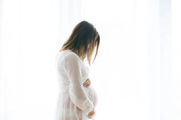 Portrait de jeune femme enceinte attrayante, debout par la victoire — Photo