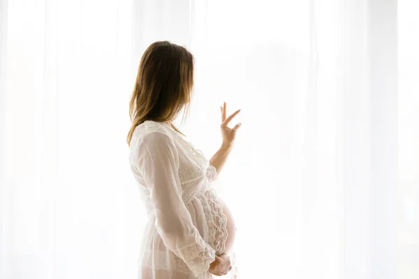 Portrait de jeune femme enceinte attrayante, debout par la victoire — Photo