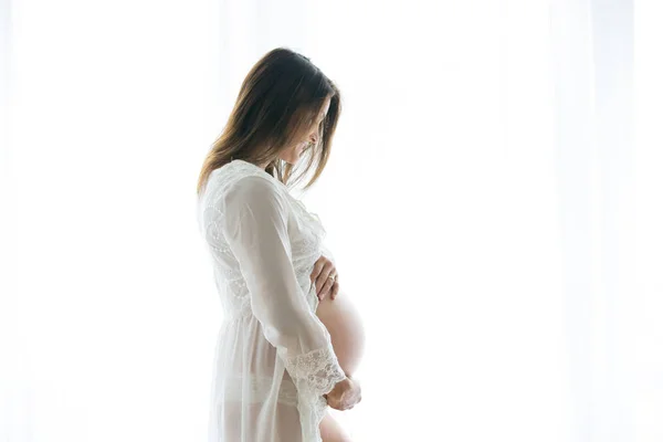 Portrait de jeune femme enceinte attrayante, debout par la victoire — Photo