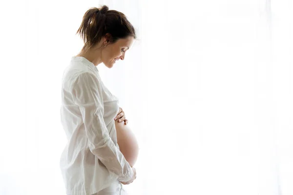 Portrait de jeune femme enceinte attrayante, debout par la victoire — Photo