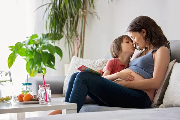 Joven embarazada, leyendo un libro en casa a su hijo — Foto de Stock