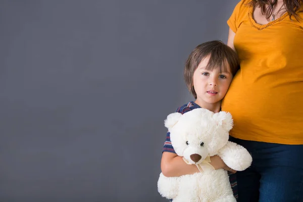 Klein kind, jongen, knuffelen zijn zwangere moeder thuis, geïsoleerd — Stockfoto