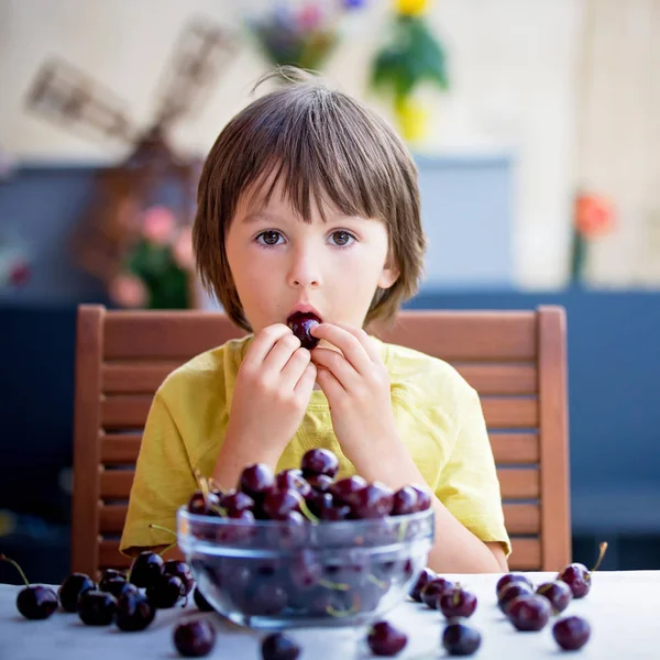 Menino bonito, comendo cereja doce ao ar livre — Fotografia de Stock
