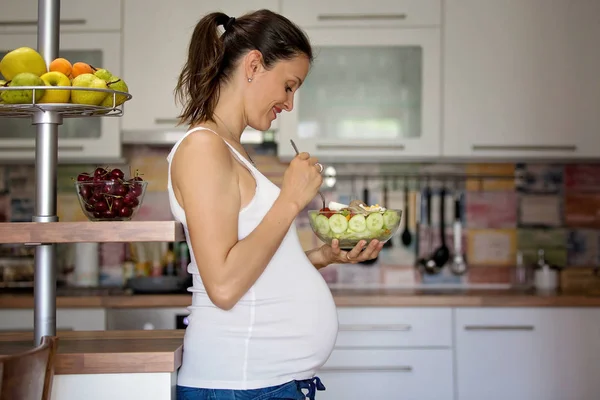 Счастливая беременная женщина ест салат дома — стоковое фото