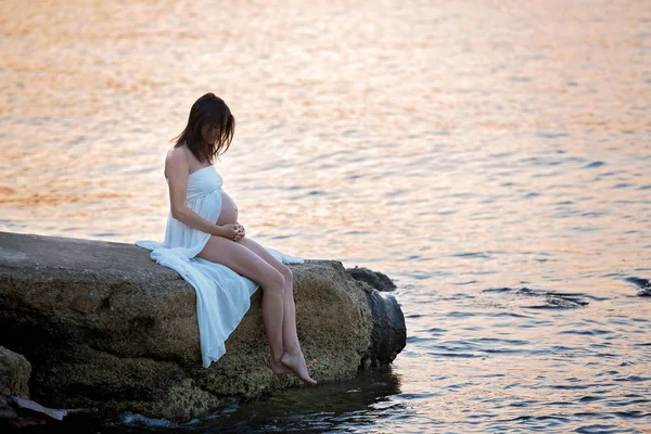 Belle femme enceinte, assise sur le rivage sur la plage sur s — Photo