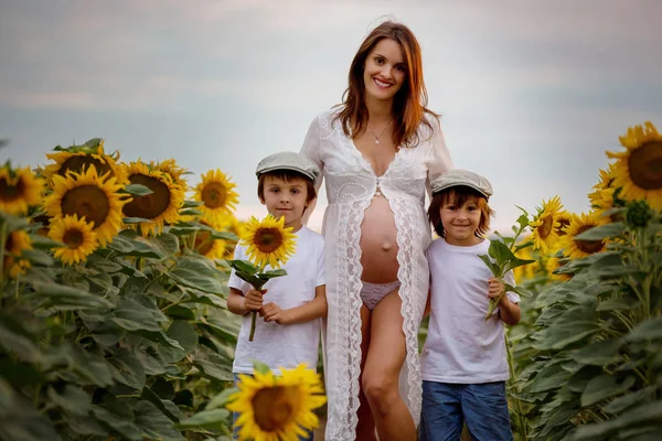 Szép terhes nő és két édes fia, átölelve boldogan — Stock Fotó