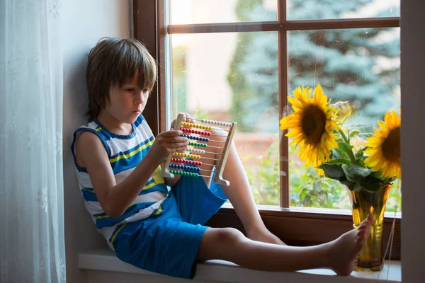 Schattig klein peuter kind, spelen met de abacus op een venster — Stockfoto