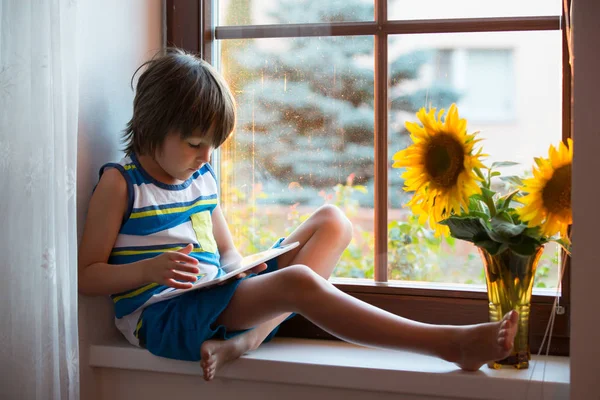 Schattig klein peuter kind, spelen op tablet op een venster — Stockfoto