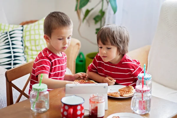 Dos niños pequeños, hermanos varones, desayunando en casa, mientras —  Fotos de Stock
