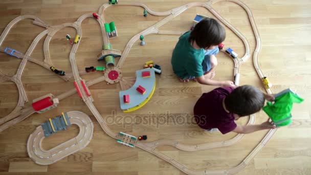 Söta förskolebarn, pojke bröder, leker med järnväg och tåg hemma, ovanifrån — Stockvideo