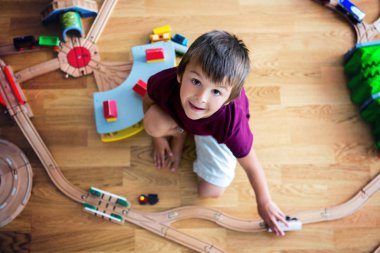 Tahta tren ve tren ile oynayan tatlı okul öncesi çocuk,