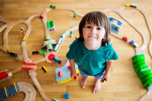 Dulce niño preescolar, jugando con el ferrocarril de madera y trenes en — Foto de Stock