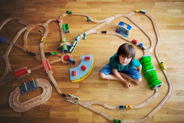 Tahta tren ve tren ile oynayan tatlı okul öncesi çocuk,