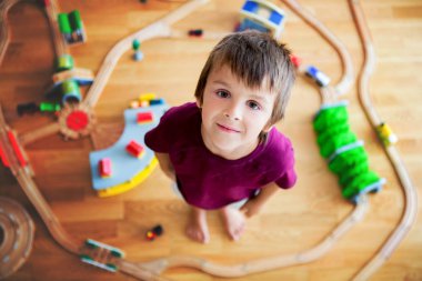 Tahta tren ve tren ile oynayan tatlı okul öncesi çocuk,