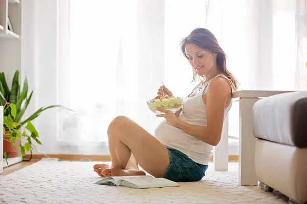 Feliz mujer embarazada comiendo ensalada en casa — Foto de Stock