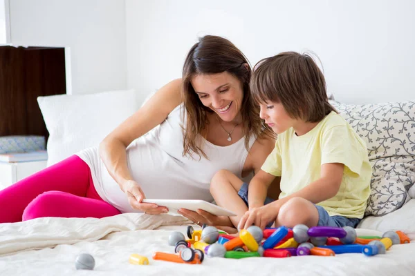 Schattige zwangere moeder en kind jongen binnenshuis samenspelen — Stockfoto