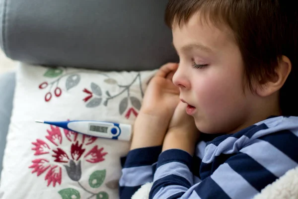 Больной маленький ребенок, мальчик, с высокой температурой спит на диване в — стоковое фото
