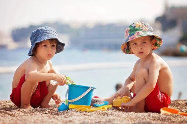 Δύο χαριτωμένα παιδιά, που παίζουν στην άμμο στην παραλία — Φωτογραφία Αρχείου