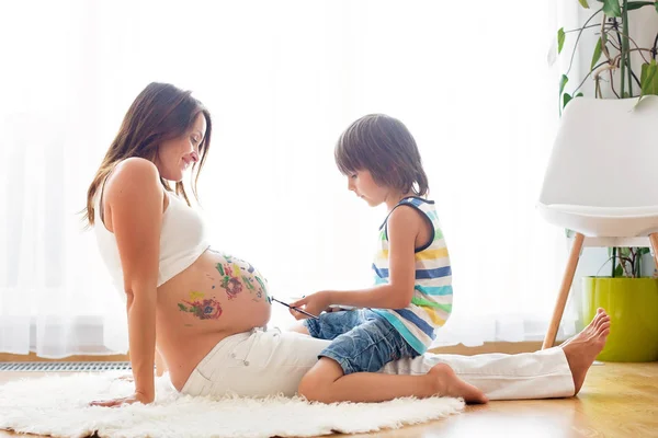 Gelukkig kind, jongen, schilderen op Mama's zwangere buik — Stockfoto