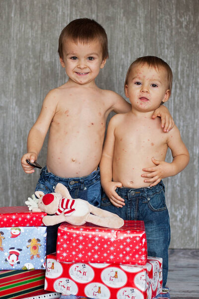 Two brothers with chickenpox on Christmas, happily looking at xm
