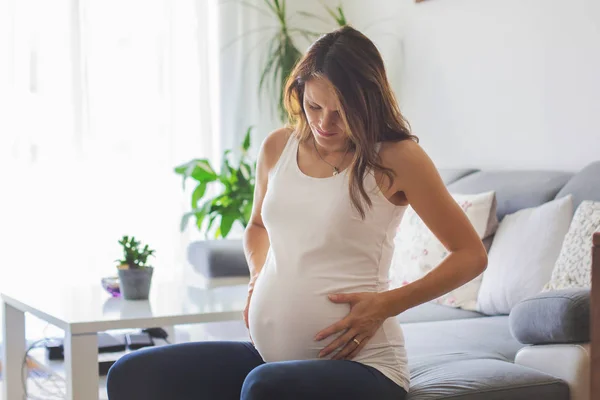 Mujer embarazada joven, con contracción dolorosa, comenzando el trabajo de parto —  Fotos de Stock