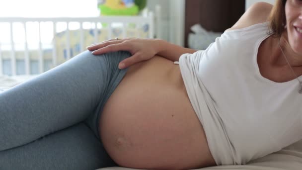 Mãe grávida e seu filho, observando a barriga da mãe e ouvindo o bebê por nascer, se divertindo juntos — Vídeo de Stock