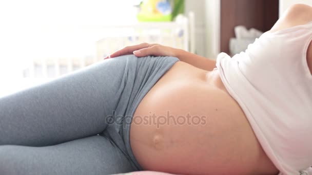 Pregnant mother and her son, watching mom's belly and listening to the unborn baby, having fun together — Stock Video