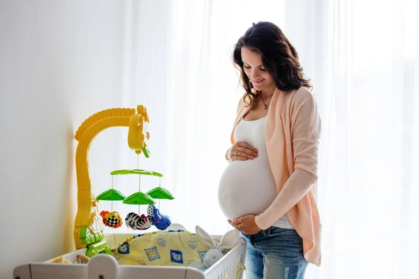 Fiatal terhes vonzó nő, neki újszülött baba ágy készül — Stock Fotó