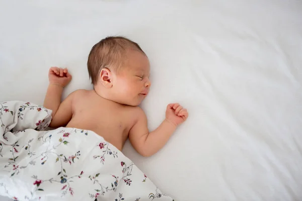 ベッドで美しい生まれたての赤ん坊の男の子。ベッドに横たわる幼児 — ストック写真