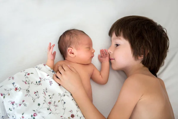 Hermoso niño, abrazando con ternura y cuidar a su bebé recién nacido —  Fotos de Stock